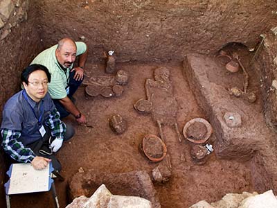 新たな発掘現場を地元メディアに公開する中村教授（写真手前）